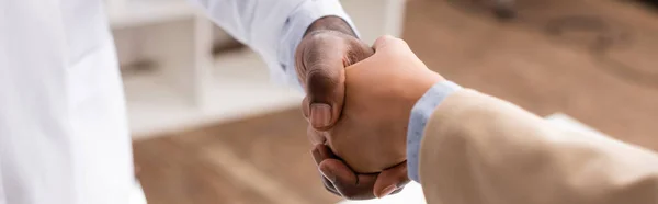 Panoramic crop of african american doctor shaking hands with patient — Stock Photo