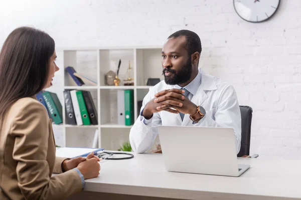 African american doctor sitting and looking at patient — Stock Photo