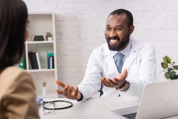Enfoque selectivo del médico afroamericano mirando al paciente y señalando con las manos - foto de stock