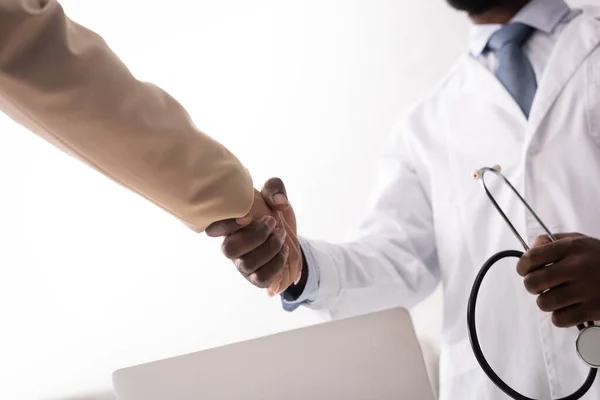 Foco seletivo do médico afro-americano segurando estetoscópio e apertando as mãos com o paciente — Fotografia de Stock