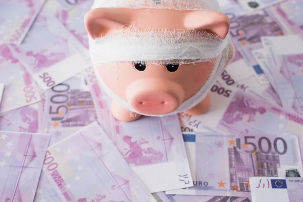 Hochwinkelblick auf Sparschwein mit Binde am Geld — Stockfoto