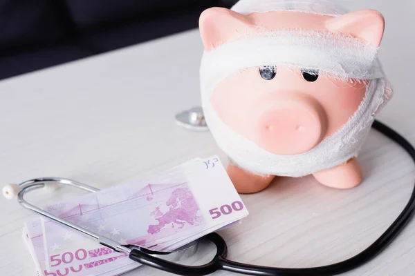 Sparschwein neben Stethoskop und Geld auf dem Tisch — Stockfoto