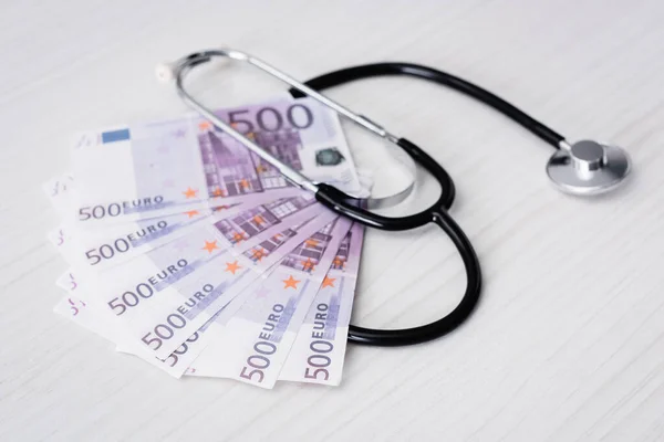 Selective focus of stethoscope and euro banknotes on white table — Stock Photo