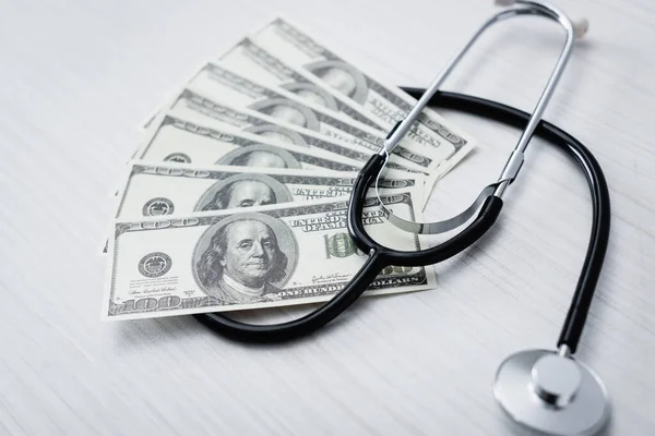 Selective focus of stethoscope and dollar banknotes on white table — Stock Photo