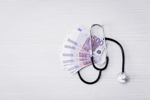 Top view of stethoscope and euro banknotes on white table — Stock Photo