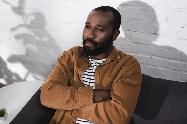 Vista de alto ângulo do homem afro-americano sentado no sofá com braços cruzados — Fotografia de Stock