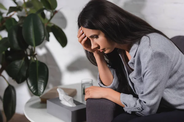 Enfoque selectivo de la mujer sentada en el sofá y la cara conmovedora - foto de stock