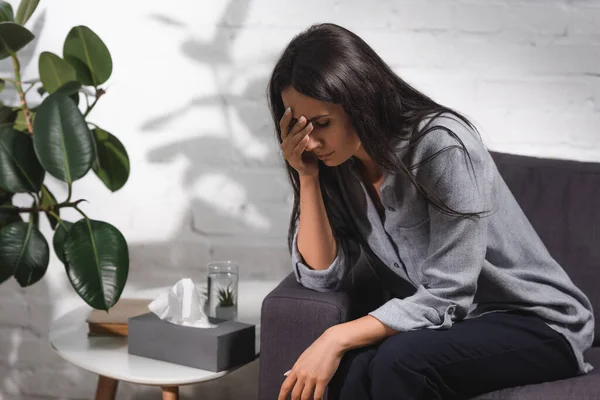 Enfoque selectivo de la mujer sentada en el sofá cerca de la mesa de café con servilletas - foto de stock