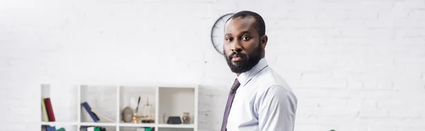 Prise de vue panoramique de psychologue afro-américain grave en tenue formelle regardant la caméra à l'hôpital — Photo de stock