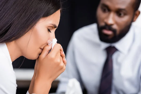 Selektiver Fokus einer weinenden Frau, die sich das Gesicht mit Papierserviette in der Nähe eines ernsthaften afrikanisch-amerikanischen Psychologen wischt — Stockfoto