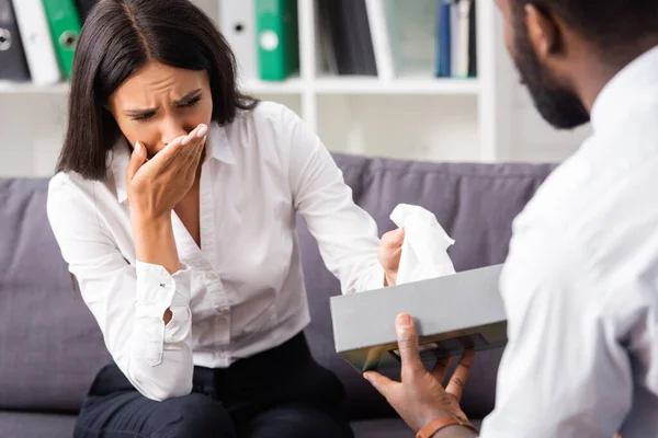 Focalizzazione selettiva dello psicologo afroamericano che dà tovagliolo di carta alla donna che piange — Foto stock