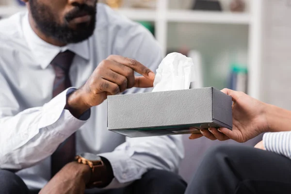 Abgeschnittene Ansicht eines afrikanisch-amerikanischen Mannes, der einer Psychologin Papierserviette aus der Hand nimmt — Stockfoto
