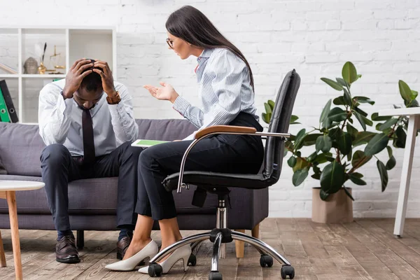 Brunette psychologist holding digital tablet with green screen while talking to stressed african American man holding hands on head — Stock Photo