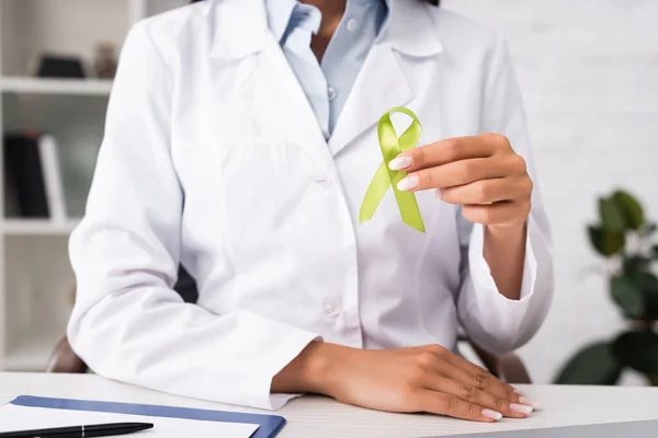 Partial view of doctor holding green awareness ribbon, mental health concept — Stock Photo
