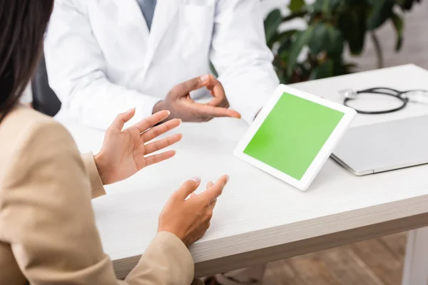 Cropped view of african american doctor in eyeglasses pointing with finger at digital tablet with green screen — Stock Photo