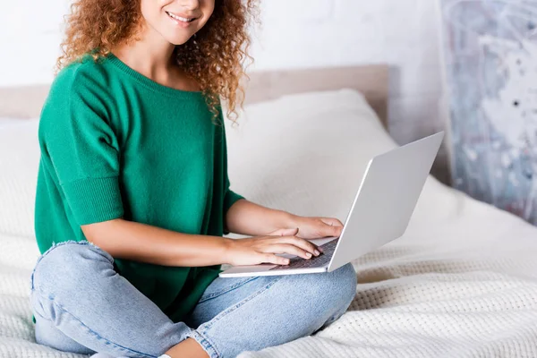 Vista ritagliata della donna dai capelli rossi che utilizza il computer portatile sul letto — Foto stock