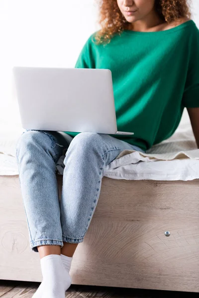 Vista ritagliata di giovane donna che utilizza il computer portatile sul letto — Foto stock