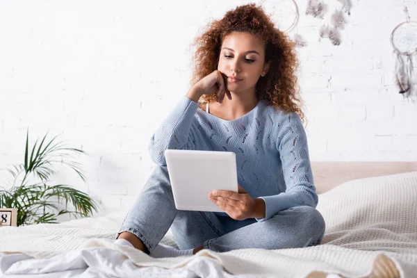 Foco seletivo da jovem mulher usando tablet digital enquanto se senta na cama — Fotografia de Stock
