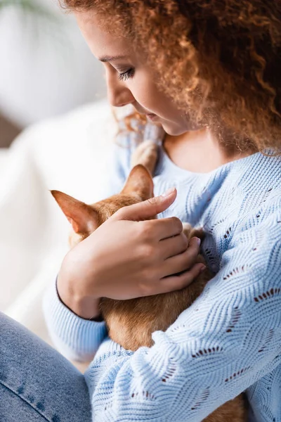 Focus sélectif de la femme aux cheveux roux embrassant le chat à la maison — Photo de stock