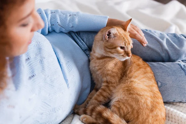 Selective focus of young woman lying near tabby cat on bed — Stock Photo