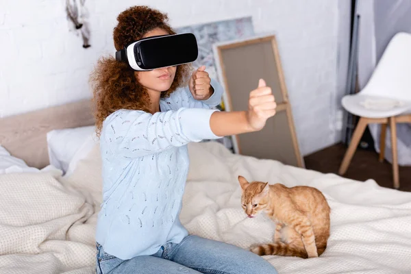 Selektiver Fokus der Frau, die Videospiel im vr-Headset in der Nähe von Katze im Schlafzimmer spielt — Stockfoto