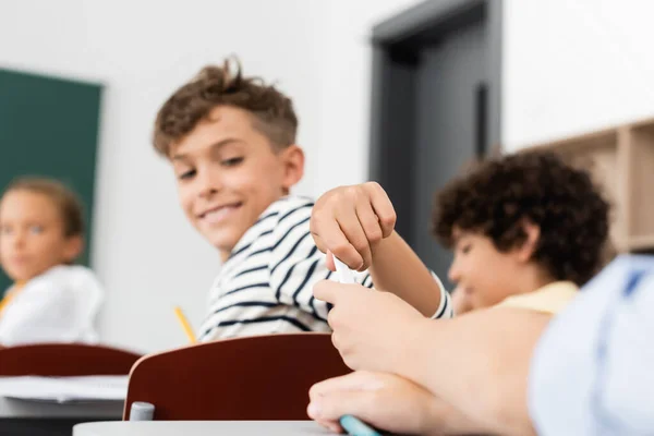 Ausgeschnittene Ansicht eines Schulkindes, das während des Unterrichts Zettel an Mitschüler in der Nähe multikultureller Schüler reicht — Stockfoto