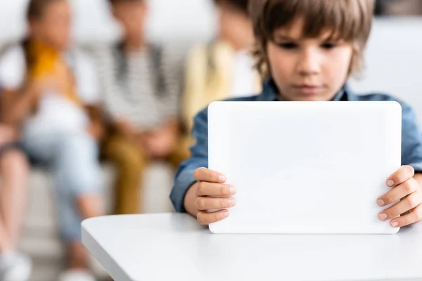 Concentration sélective de l'écolier en utilisant une tablette numérique au bureau dans la salle de classe — Photo de stock