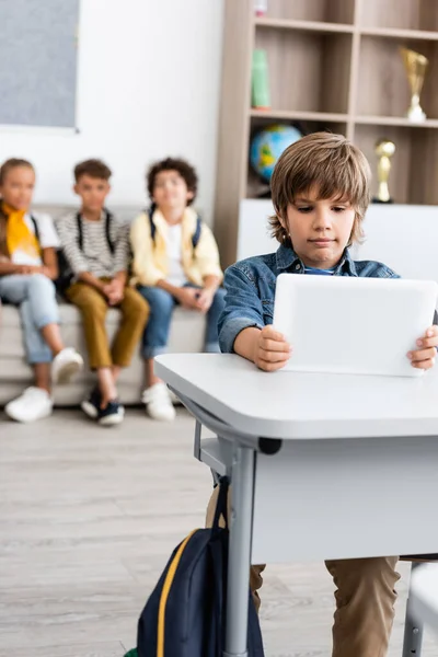 Concentration sélective de l'écolier tenant une tablette numérique au bureau dans la salle de classe — Photo de stock
