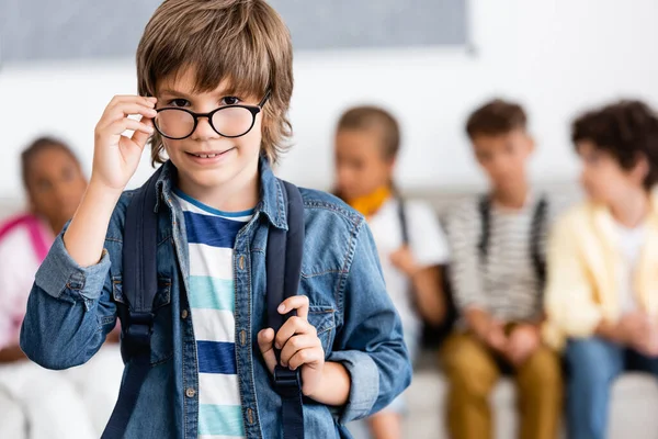 Selective focus of schoolboy with backpack and eyeglasses in classroom — Stock Photo