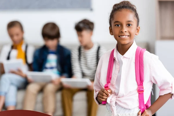 Enfoque selectivo de la colegiala afroamericana mirando la cámara en el aula - foto de stock