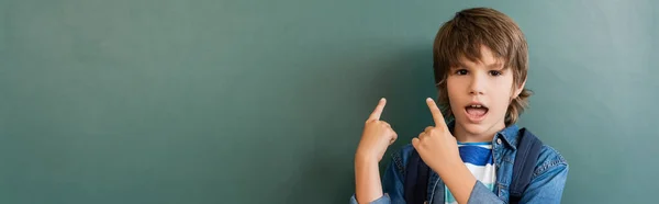 Intestazione del sito web di scolaro eccitato che punta con le dita alla lavagna verde — Foto stock