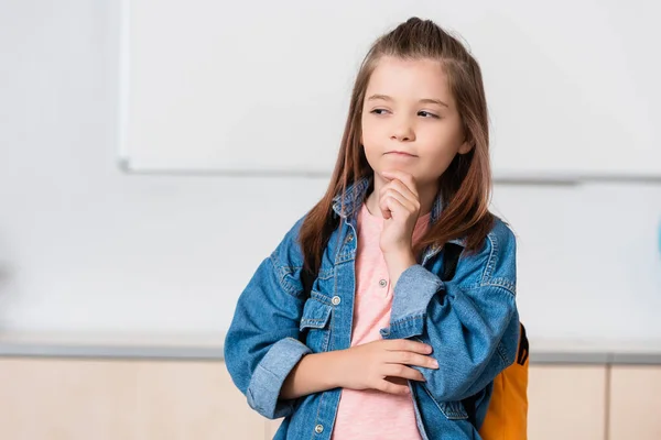 Pensive schoolgirl with backpack looking away in stem school — Stock Photo