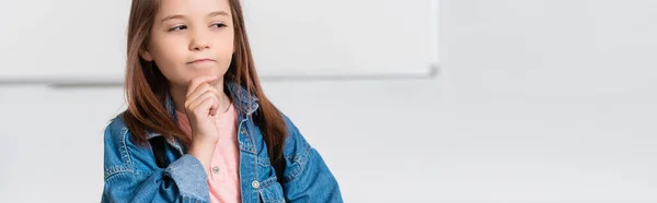 Panoramic orientation of pensive schoolgirl looking away in classroom — Stock Photo