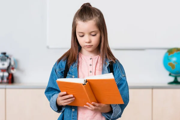 Estudante com mochila leitura livro na escola tronco — Fotografia de Stock