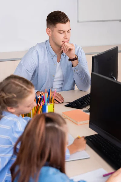 Focus selettivo dell'insegnante che utilizza il computer vicino alle studentesse in classe — Foto stock