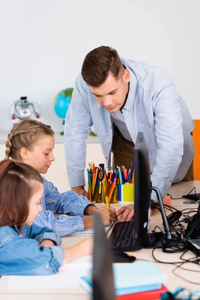 Focus selettivo dell'insegnante in piedi vicino alle studentesse durante la lezione nella scuola staminale — Foto stock