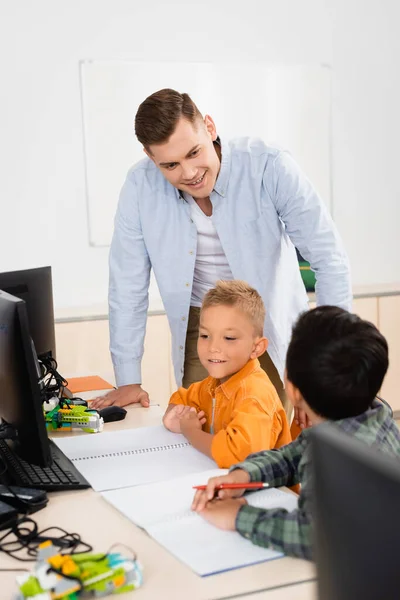 Enfoque selectivo de profesor mirando asiático escolar durante lección en tallo escuela - foto de stock