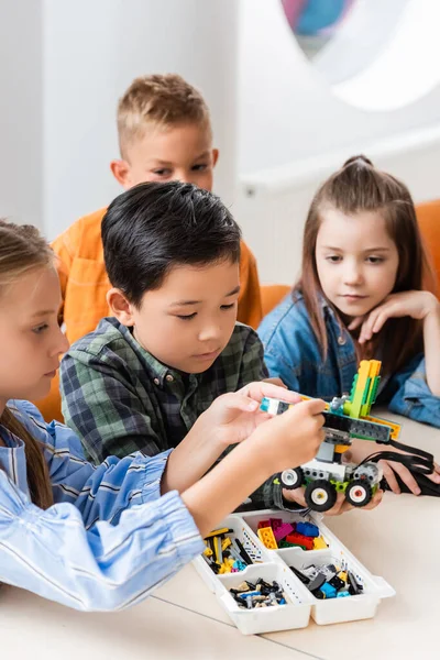 Focus selettivo dei bambini multietnici con blocchi di costruzione robot di modellazione nella scuola staminale — Foto stock