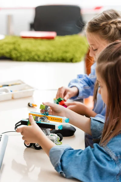 Selective focus of schoolkids playing with building blocks while modeling robot in school — Stock Photo