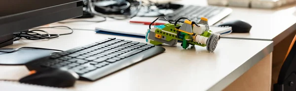 Panoramic shot of robot near computer on table in stem school — Stock Photo