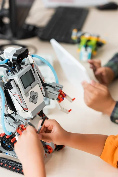 Обрезанный вид школьников, программирующих роботов во время урока в начальной школе — стоковое фото