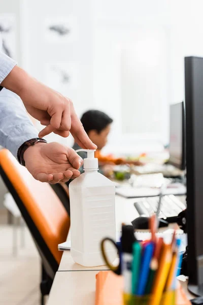 Selective focus of teacher using hand sanitizer near computers in school — Stock Photo