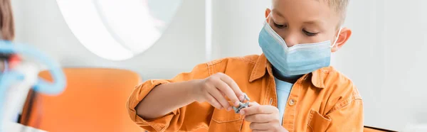 Panoramic shot of schoolboy in medical mask making robot in stem school — Stock Photo