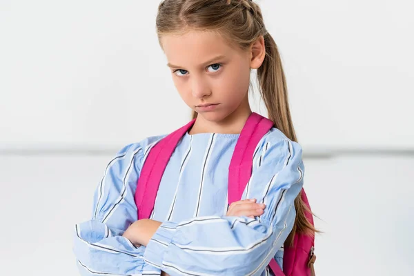 Selective focus of confident schoolkid with backpack looking at camera in school — Stock Photo