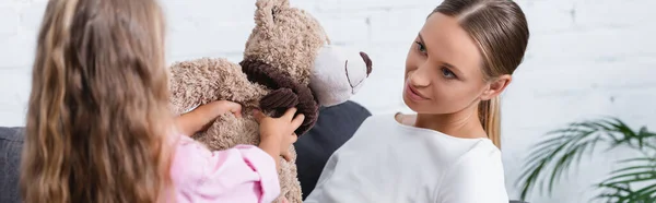 Colpo panoramico di ragazza che dà orsacchiotto alla madre a casa — Foto stock