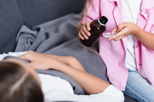 Selective focus girl holding bottle of syrup near sick mother — Stock Photo