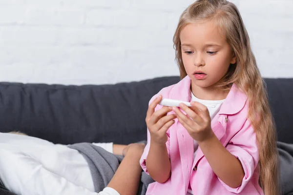 Selective focus of daughter holding thermometer near diseased mother — Stock Photo