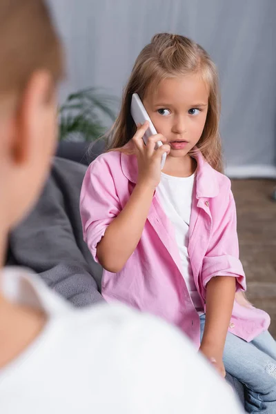 Foco seletivo da menina falando no smartphone perto da mãe doente no sofá — Fotografia de Stock