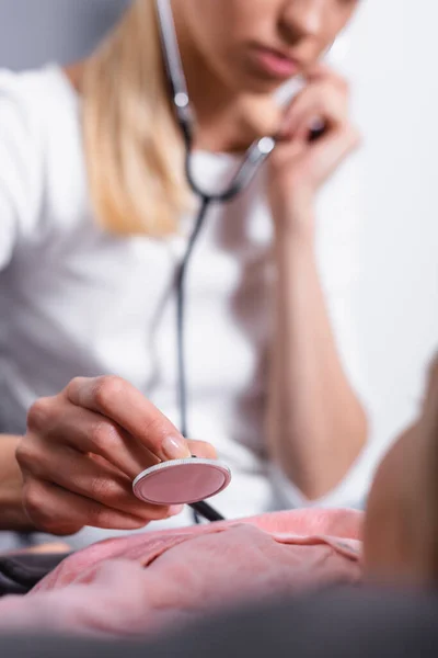 Focus selettivo della donna che utilizza lo stetoscopio sulla figlia malata — Foto stock