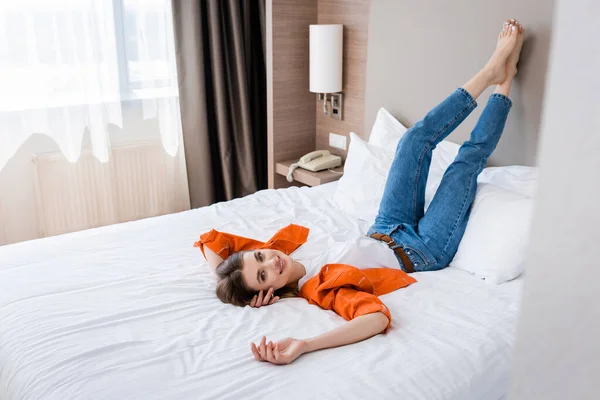 Jovem mulher satisfeita descansando na cama no quarto do hotel — Fotografia de Stock